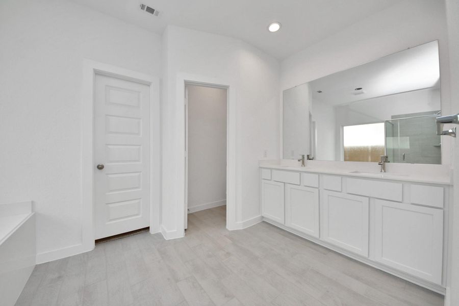 Elevate your daily routine at the elegant vanity, now equipped with double sinks, light countertops, modern hardware, and beautiful recessed lights.