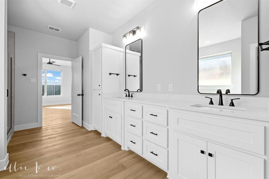 Bathroom featuring double vanity, light wood-style flooring, a ceiling fan, and a shower with door