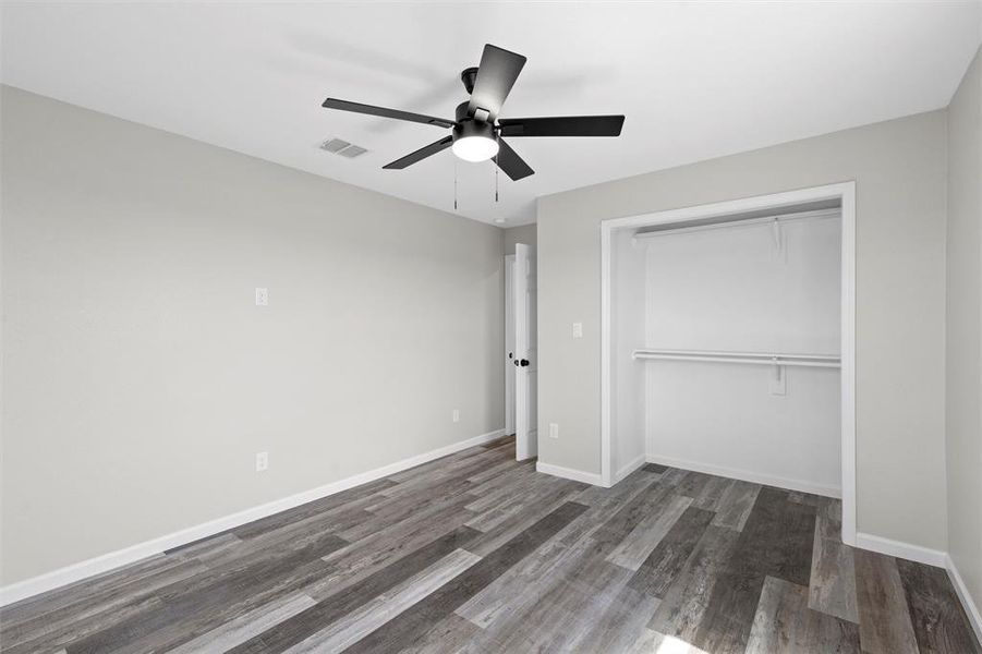 Unfurnished bedroom featuring dark wood-style floors, ceiling fan, and a closet Unfurnished bedroom featuring dark wood-style floors, ceiling fan, and a closet