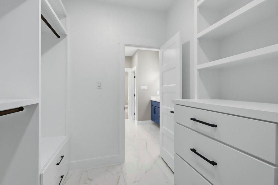 Another view of the massive primary closet showing its dual custom built-in dressers and extensive storage layout, leading seamlessly right into the luxury en-suite bathroom. Another view of the massive primary closet showing its dual custom built-in dressers and extensive storage layout, leading seamlessly right into the luxury en-suite bathroom.