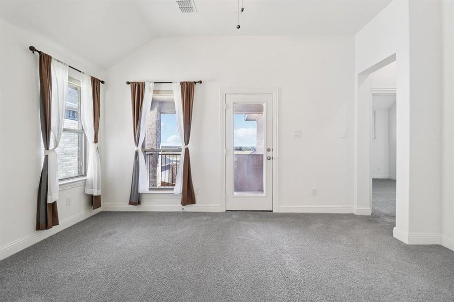 Carpeted empty room with vaulted ceiling and a ceiling fan Carpeted empty room with vaulted ceiling and a ceiling fan