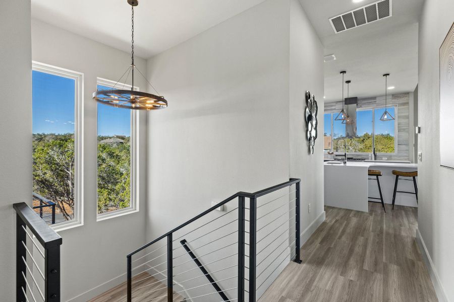 Corridor with wood finished floors, a notable chandelier, an upstairs landing, and visible vents