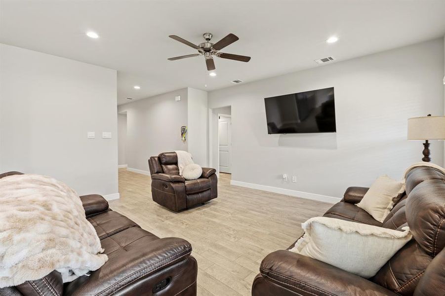 Spacious living area featuring light-toned wood-finish flooring, recessed lighting, and a ceiling fan Spacious living area featuring light-toned wood-finish flooring, recessed lighting, and a ceiling fan
