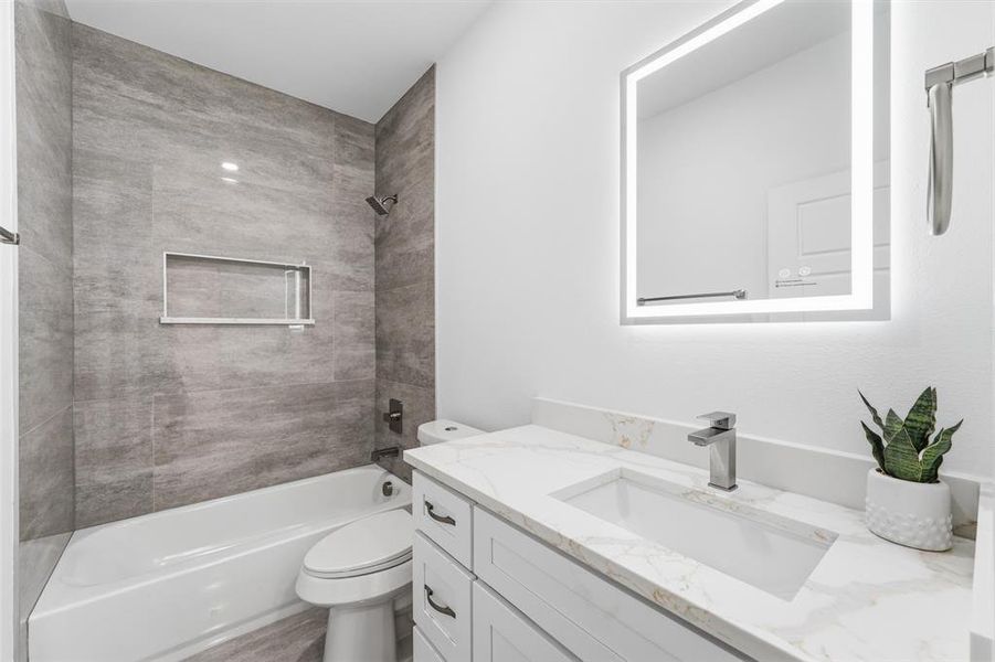 Bathroom featuring a tub/shower combination with gray tile surround and a built-in niche