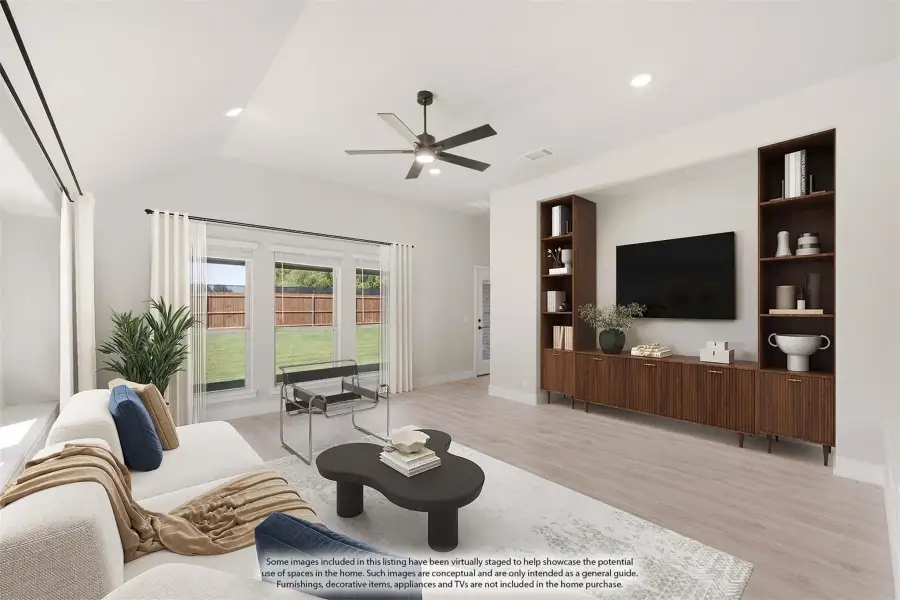Open living room with vaulted ceiling, ceiling fan, built-in wood shelving, and light hardwood floors