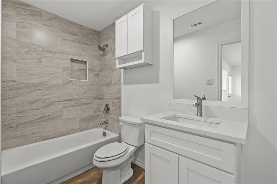 Full bathroom with vanity, toilet, hardwood / wood-style flooring, and tiled shower / bath combo