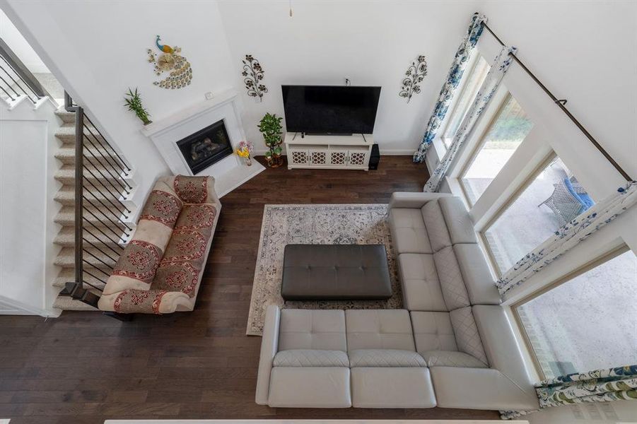 Living room with stairway, wood finished floors, and a glass covered fireplace