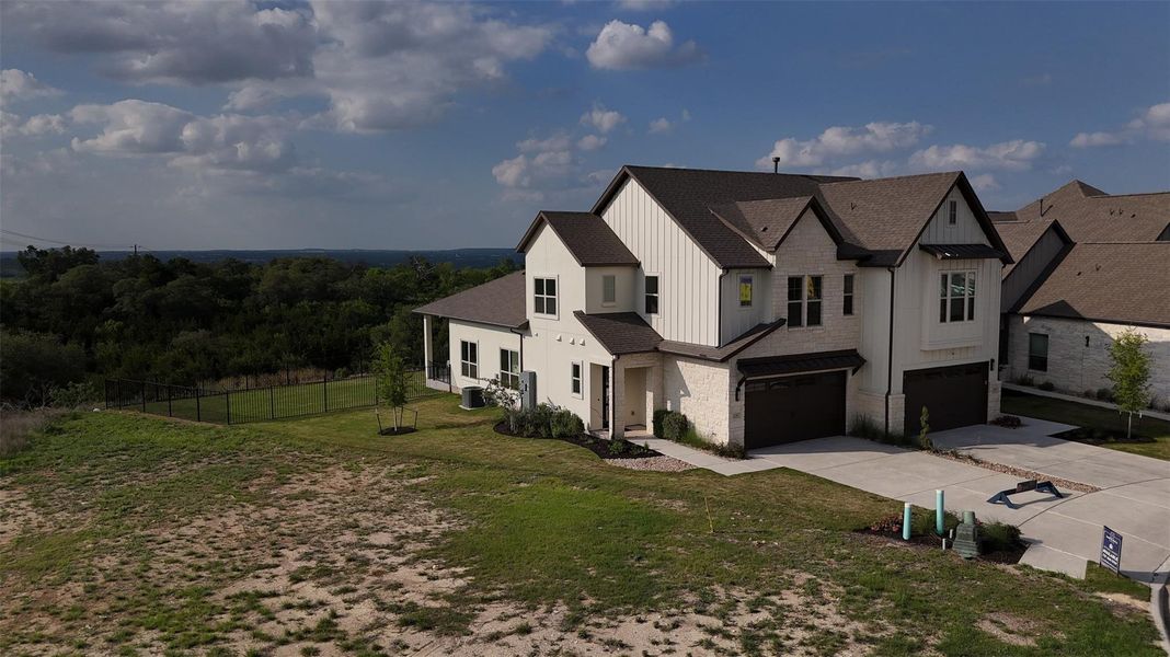 Contemporary two-story property with a dark brown roof and light-colored siding, featuring two prominent garage doors and a paved driveway