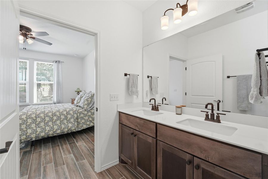 Full bathroom with ensuite bath, wood finish floors, double vanity, and ceiling fan