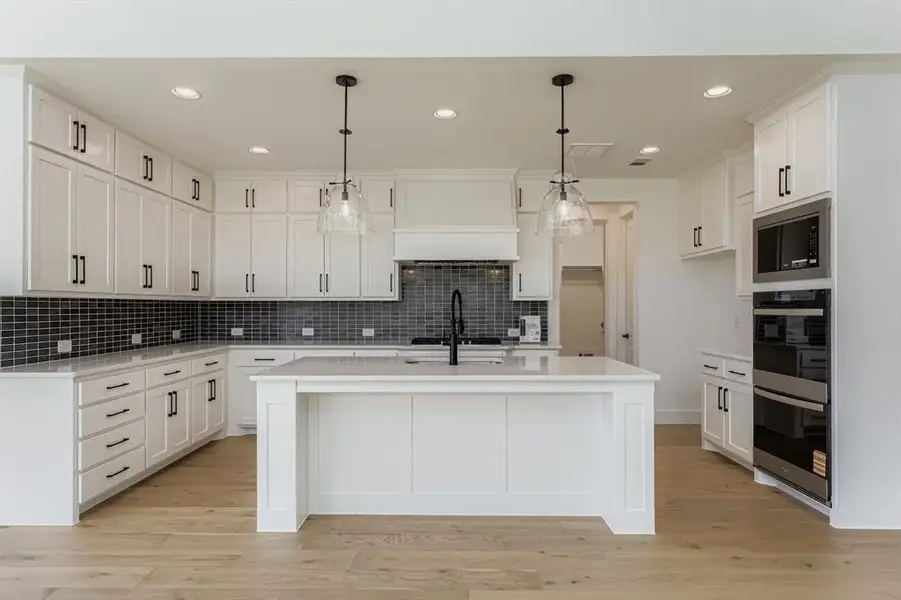 Kitchen with recessed lighting, appliances with stainless steel finishes, decorative light fixtures, white cabinets, and light wood-type flooring