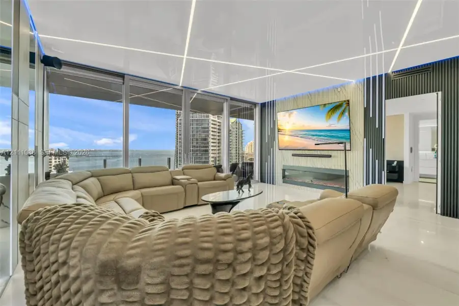 Floor-to-ceiling windows, linear recessed ceiling lighting, wall-mounted linear fireplace, textured feature wall, and polished stone flooring Floor-to-ceiling windows, linear recessed ceiling lighting, wall-mounted linear fireplace, textured feature wall, and polished stone flooring