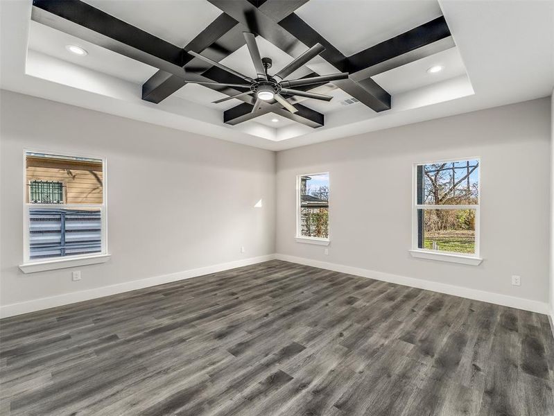 Empty room featuring ceiling fan, coffered ceiling, and dark hardwood / wood-style floors