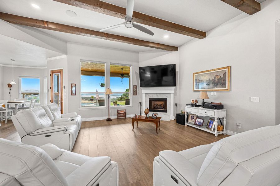 A spacious living room features soaring ceilings with exposed beams and a fireplace, offering abundant natural light and an impressive view. A spacious living room features soaring ceilings with exposed beams and a fireplace, offering abundant natural light and an impressive view.