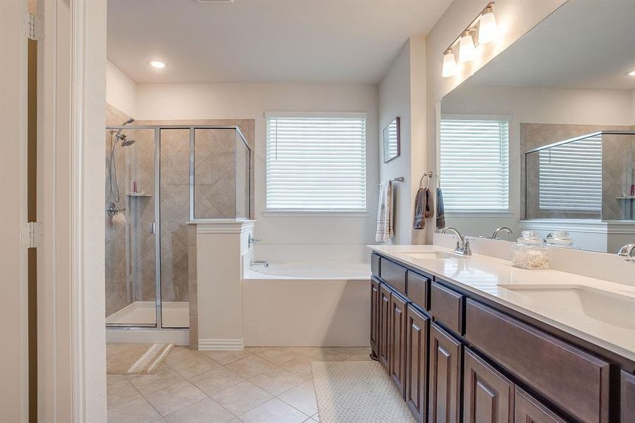 Bathroom with a garden tub, light tile patterned floors, a shower stall, double vanity, and plenty of natural light Bathroom with a garden tub, light tile patterned floors, a shower stall, double vanity, and plenty of natural light