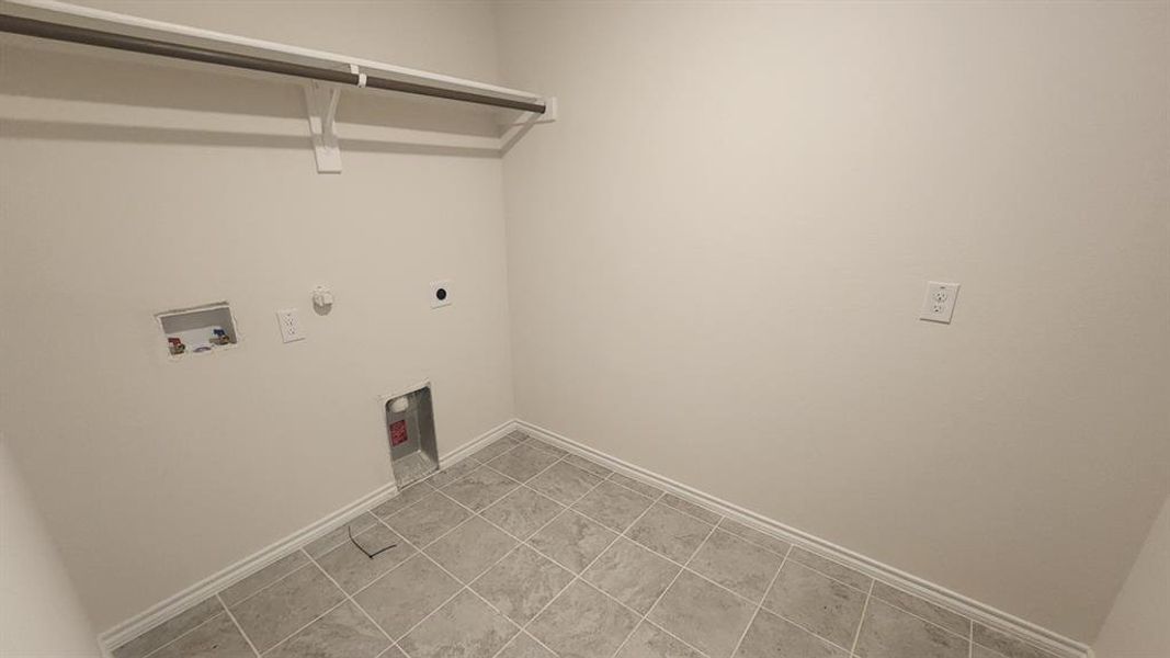 Dedicated laundry room featuring tile flooring, white baseboards, and a built-in hanging rod