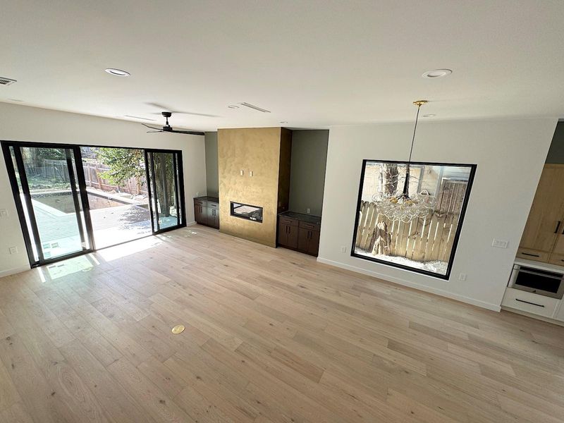 Unfurnished living room featuring recessed lighting, ceiling fan with notable chandelier, baseboards, and light wood finished floors