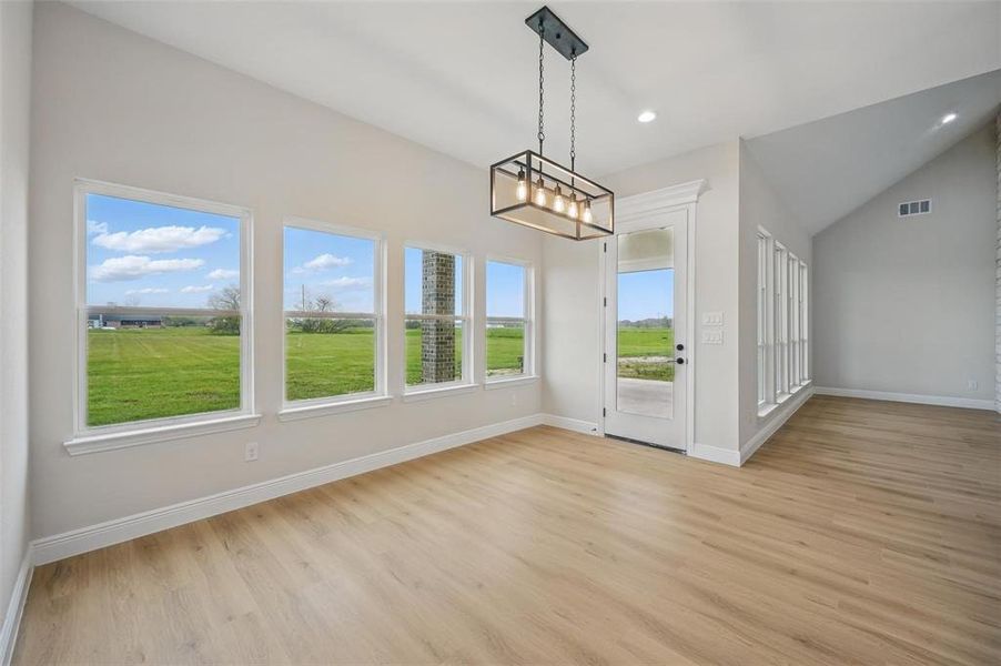 Unfurnished dining area featuring lofted ceiling, light wood-type flooring, and recessed lighting Unfurnished dining area featuring lofted ceiling, light wood-type flooring, and recessed lighting