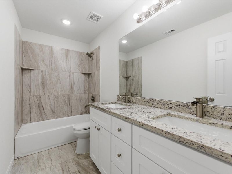 The secondary bathroom is designed with sleek finishes, granite counters, and dual sinks creating elevated everyday living.