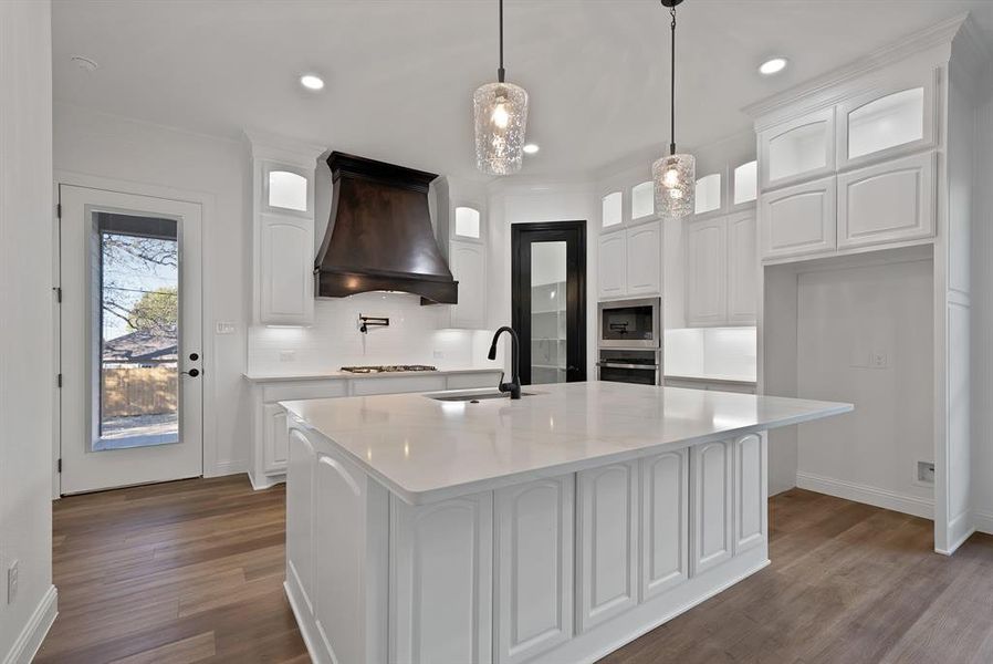 Kitchen with white cabinetry, glass insert cabinets, dark wood-type flooring, pendant lighting, and custom exhaust hood