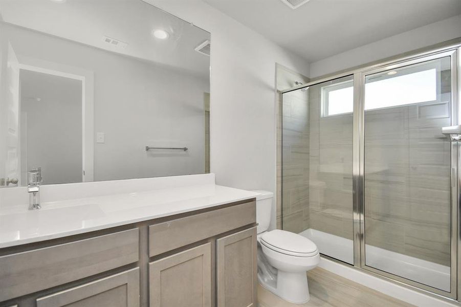 Secondary bathroom equipped with a Bath/shower combo surrounded by tasteful tile. Light wood cabinets, coupled with a gorgeous countertop, elevate the space, cultivating a truly welcoming atmosphere.