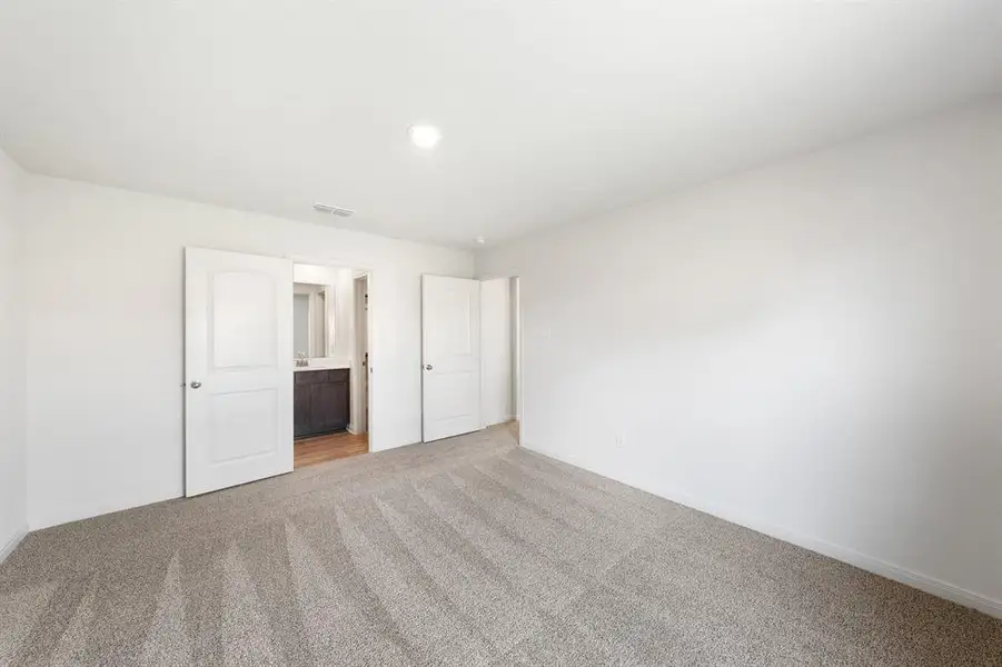 Bedroom with light colored carpet and connected bathroom