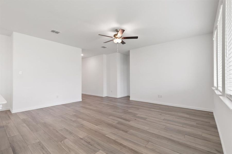 Empty room with ceiling fan and light hardwood / wood-style flooring