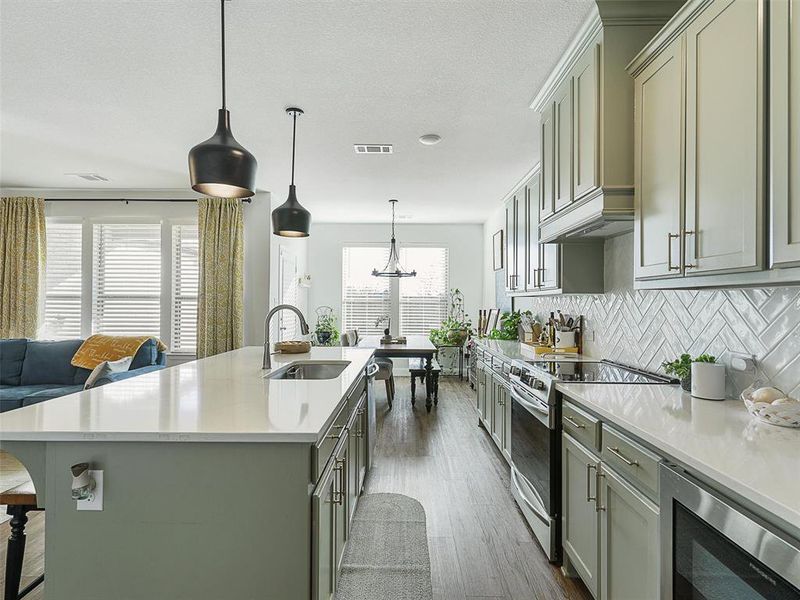 Kitchen with appliances with stainless steel finishes, decorative backsplash, sink, hanging light fixtures, and gray cabinets