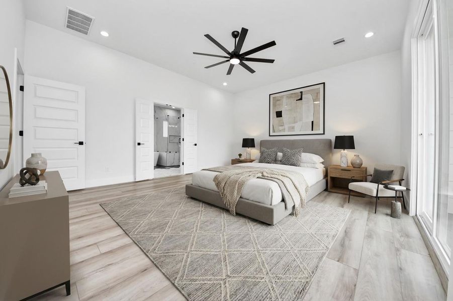 This spacious and modern bedroom features a neutral color palette with light wood flooring and a geometric rug. The room includes a sleek ceiling fan, ample natural light from large windows, and a stylish ensuite bathroom accessed through double doors.