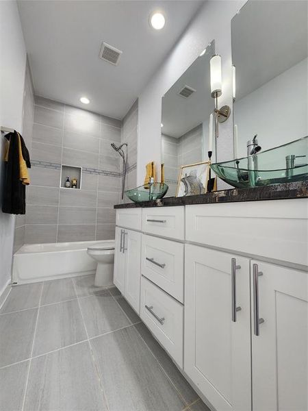 Full bathroom with tiled shower / bath combo, tile patterned floors, vanity, and toilet