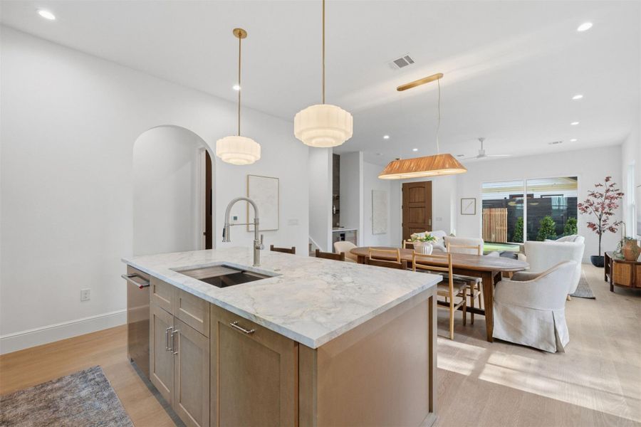 An open-concept living area features a bright kitchen island with a deep sink and an inviting dining space.