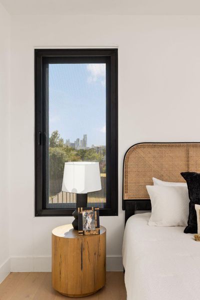 Cityscape views from this naturally illuminated bedroom featuring light hardwood floors.
