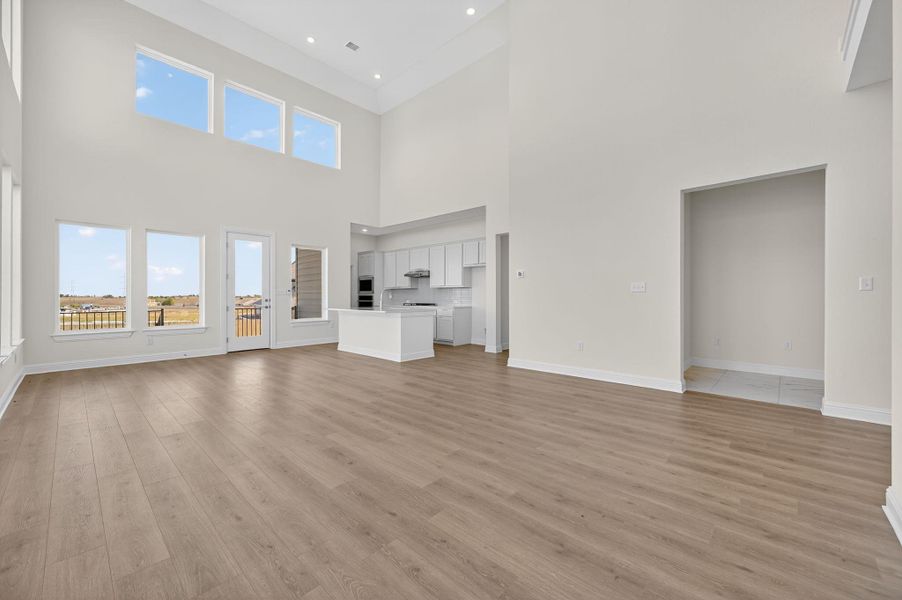 Unfurnished living room featuring light wood-style floors, a high ceiling, and recessed lighting