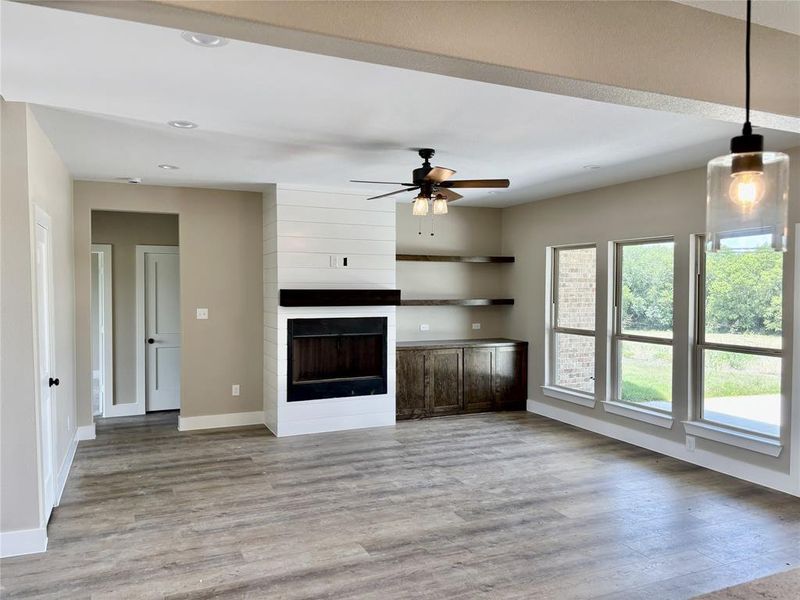 Unfurnished living room featuring wood finished floors, ceiling fan, recessed lighting, and a large fireplace Unfurnished living room featuring wood finished floors, ceiling fan, recessed lighting, and a large fireplace
