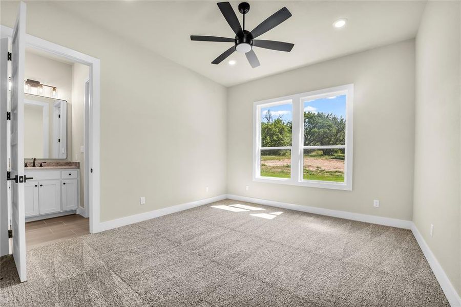 Unfurnished bedroom with light carpet, ceiling fan, recessed lighting, and ensuite bath