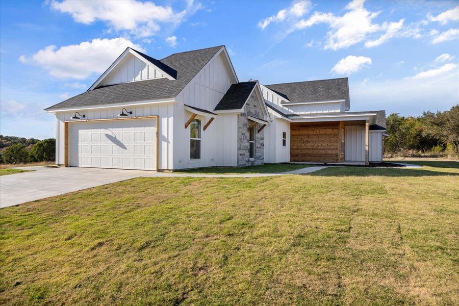 Modern farmhouse style home featuring board and batten siding, roof with shingles, a front yard, concrete driveway, and an attached garage