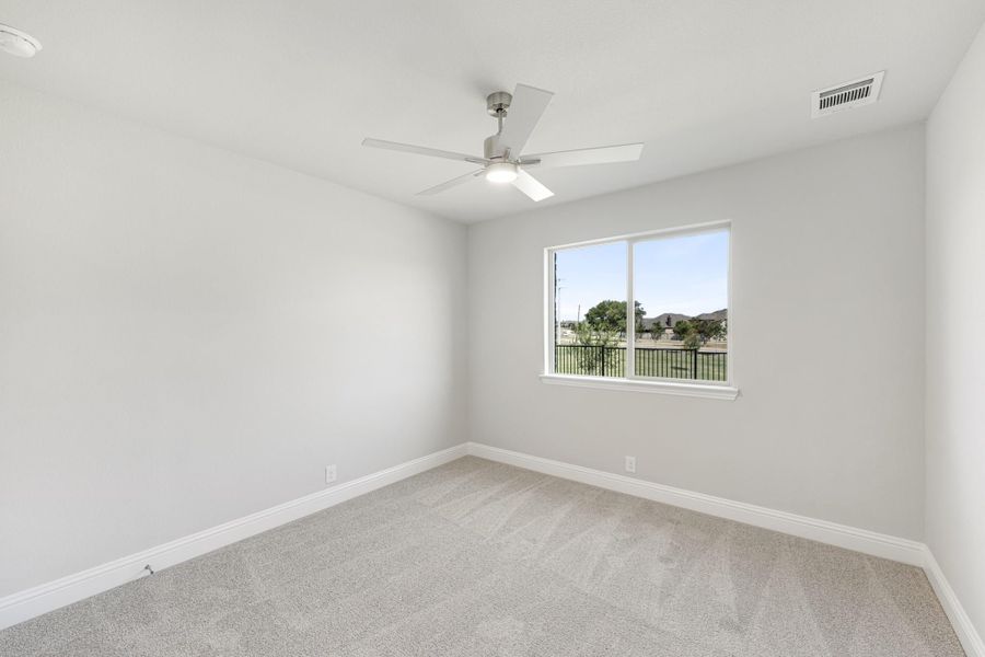 Empty bedroom with gray carpet, ceiling fan, and single window with outdoor view
