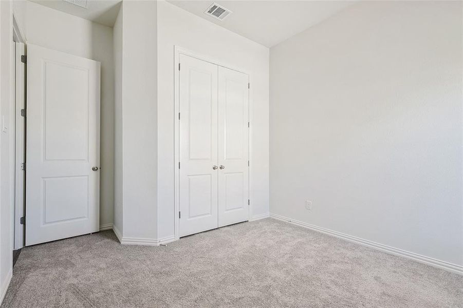 Unfurnished bedroom with light colored carpet and a closet