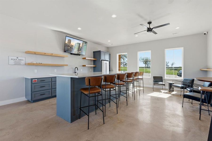 An inviting common area features a large kitchen island, sleek bar stools, and abundant natural light from multiple windows.