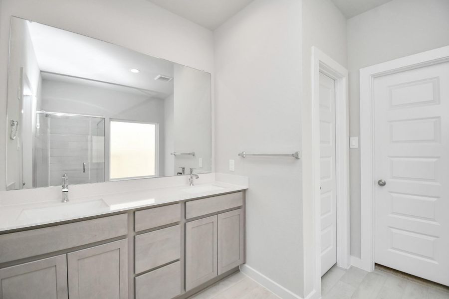 Escape to a spa-like oasis in this primary bathroom. Enjoy a walk-in shower with tile surround, a separate garden tub with custom detailing, and an elegant vanity featuring light countertops, modern hardware, and beautiful recessed lights. Experience luxury and relaxation in every detail. Sample photo of completed home with similar floor plan. Actual colors and selections may vary.