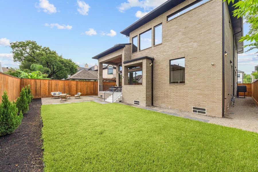 [REAR ELEVATION] The striking rear elevation showcases the home's timeless modern brick architecture, enhanced by dramatic windows that frame lush green views while filling the interiors with natural light.