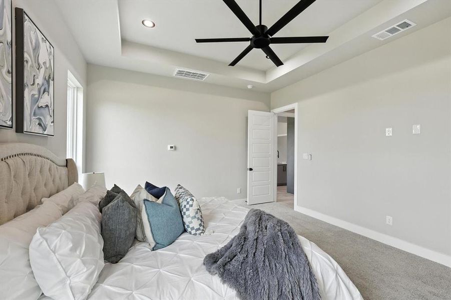 Bedroom featuring light colored carpet, a tray ceiling, recessed lighting, and a ceiling fan Bedroom featuring light colored carpet, a tray ceiling, recessed lighting, and a ceiling fan