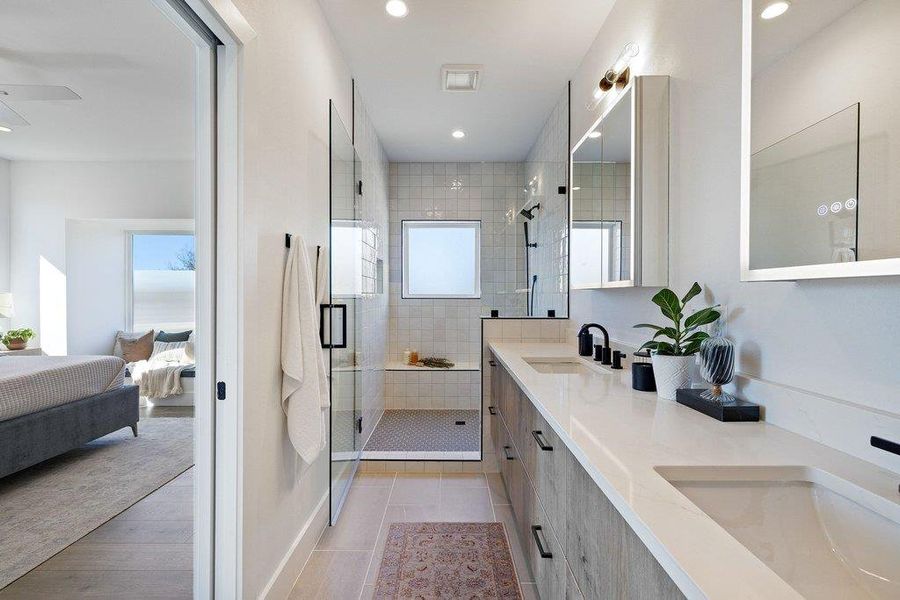 Large walk in shower with bench, dual shower fixture and hand-held wand, shower controls contently located on half wall immediately to the right of the shower door.