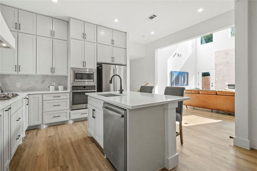Kitchen with a breakfast bar area, stainless steel appliances, recessed lighting, tasteful backsplash, and light wood finished floors