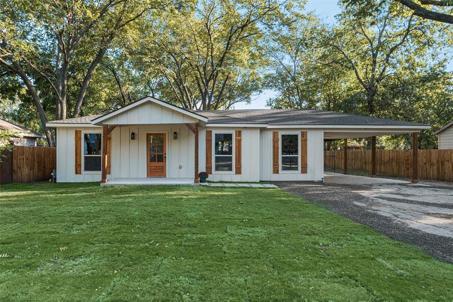 Ranch-style house featuring a porch, a front yard, and a carport