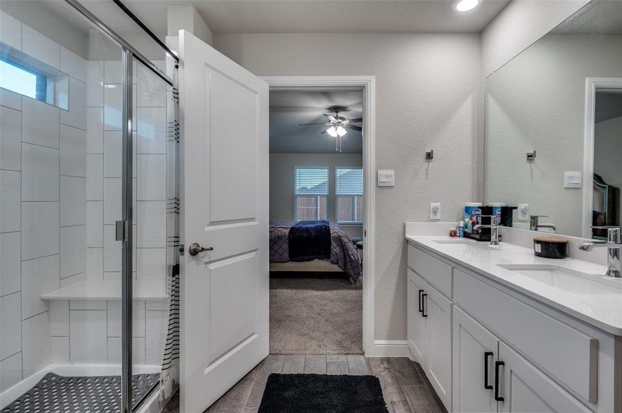 Full bath with double vanity, ensuite bathroom, a stall shower, and a ceiling fan