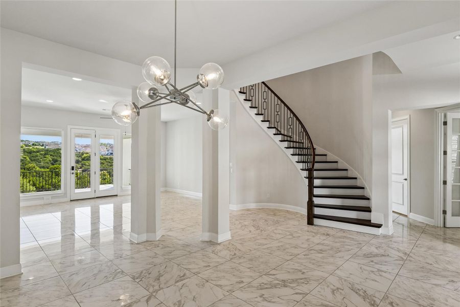 A grand curved staircase and luminous tiled floors define this versatile interior space with an inviting outdoor view.