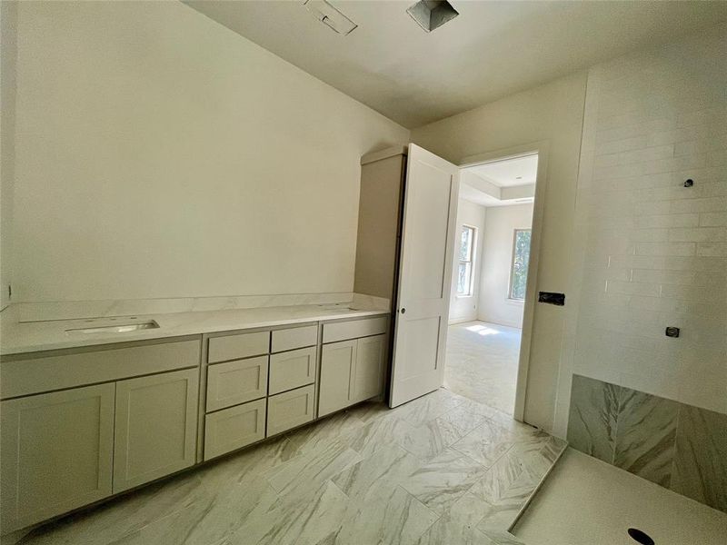 Bathroom featuring a tile shower, tile patterned flooring, and vanity