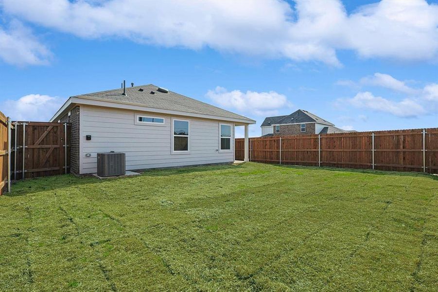 Rear view of house featuring central AC and a yard