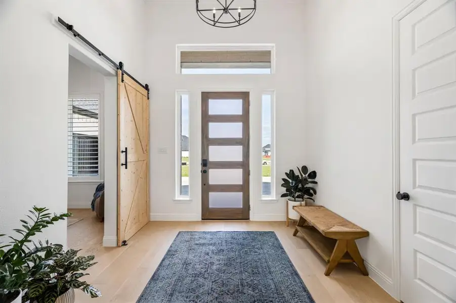 Step inside to find a private home office behind a stylish barn door on your right, balanced by convenient storage and a coat closet on your left.