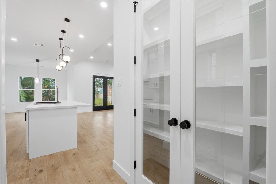 Organization Made Beautiful. Tucked right off the kitchen, these elegant double glass doors open to reveal custom built-in shelving, providing a highly functional, showcase-worthy pantry space.